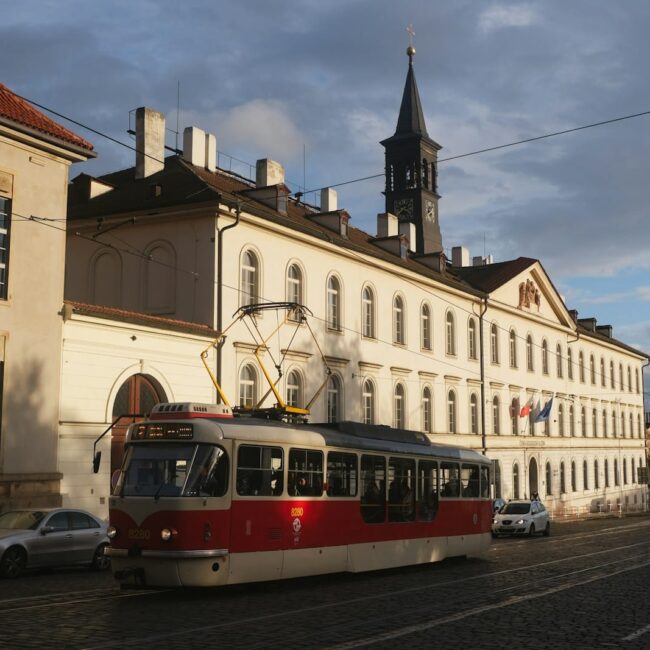 A vintage tram drives past buildings on a street in Prague