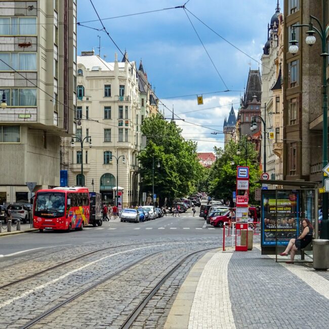 Red bus on a city street with tram tracks.