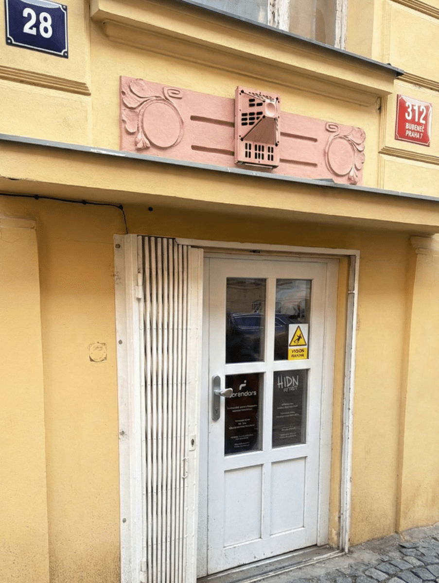 Red sign next to blue sign on a street in Prague